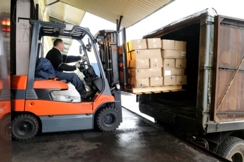 Electric forklift in warehouse loading cardboard boxes